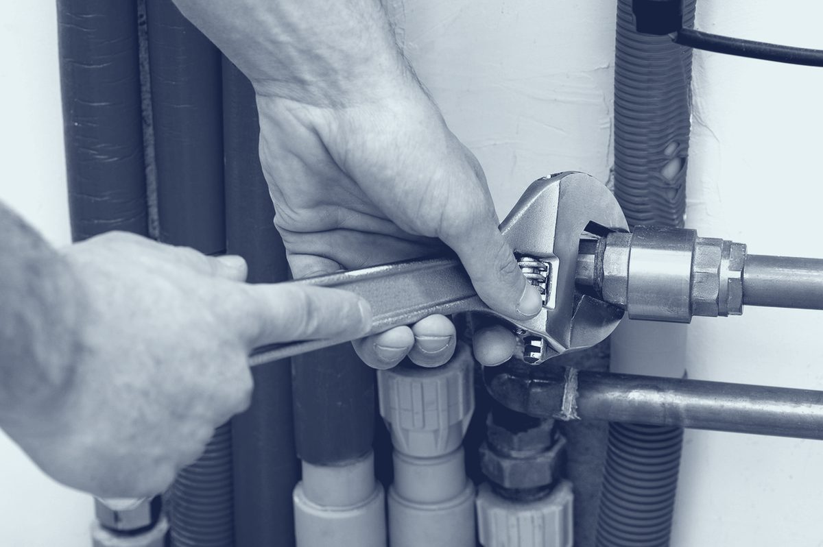 Plumber joining new supply pipe with a wrench